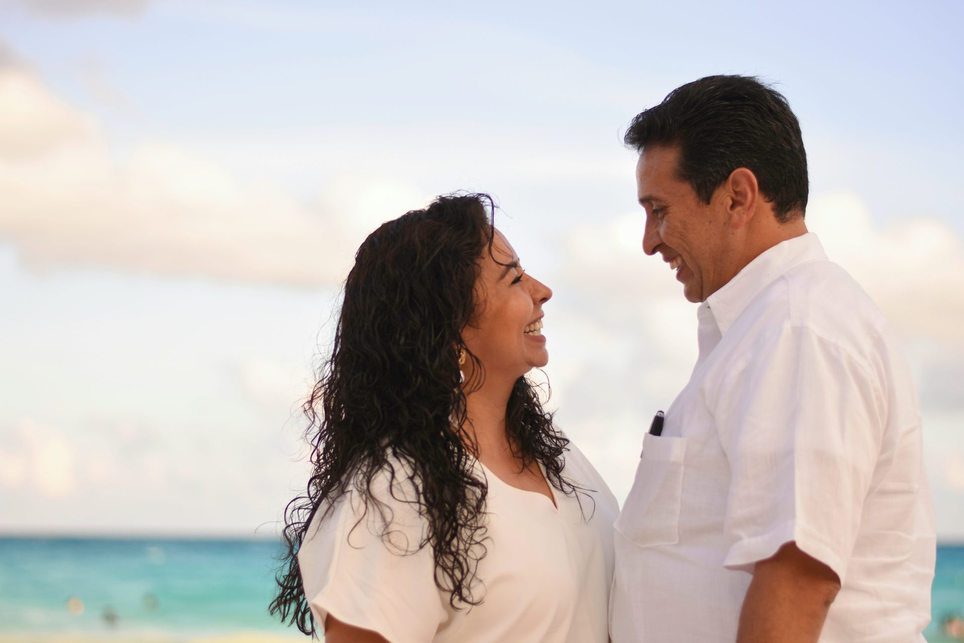 Un homme et une femme se font face en souriant à la plage